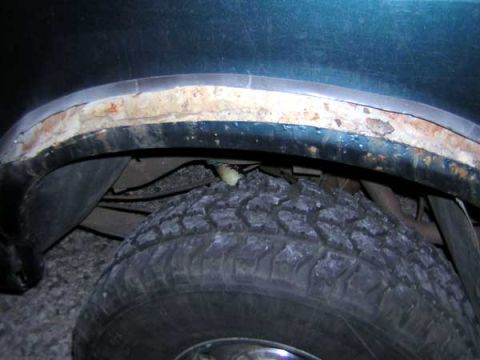 1995 Ford Bronco - Close-up of a rusty rear fender and tire, showing significant wear and tear.