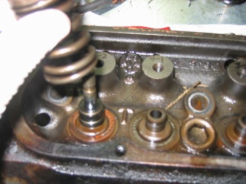1992 Ford Bronco - Close-up of a disassembled cylinder head showing valve springs, valve stems, and combustion chamber ports, with cast numbers (2, 4) visible…
