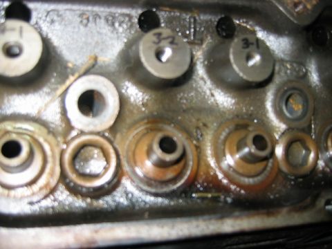 1992 Ford Bronco - Close-up of a metal engine cylinder head surface showing valve seats, spring seats, and bolt holes, with hand-written markings '3-2' and '3…