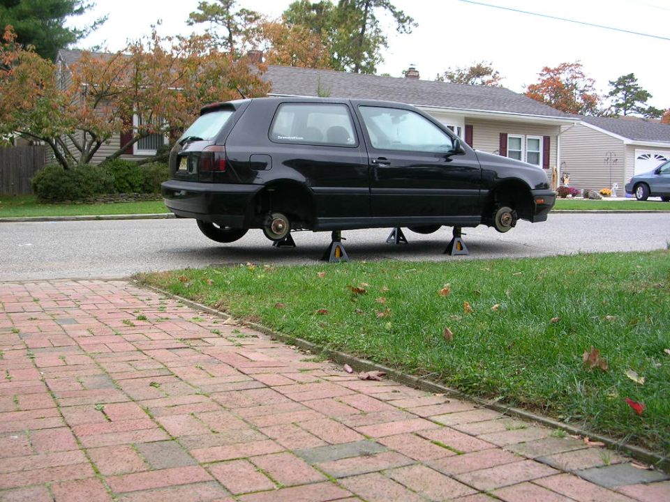 Black VW Mk3 Golf on four jack stands with wheels off in a driveway