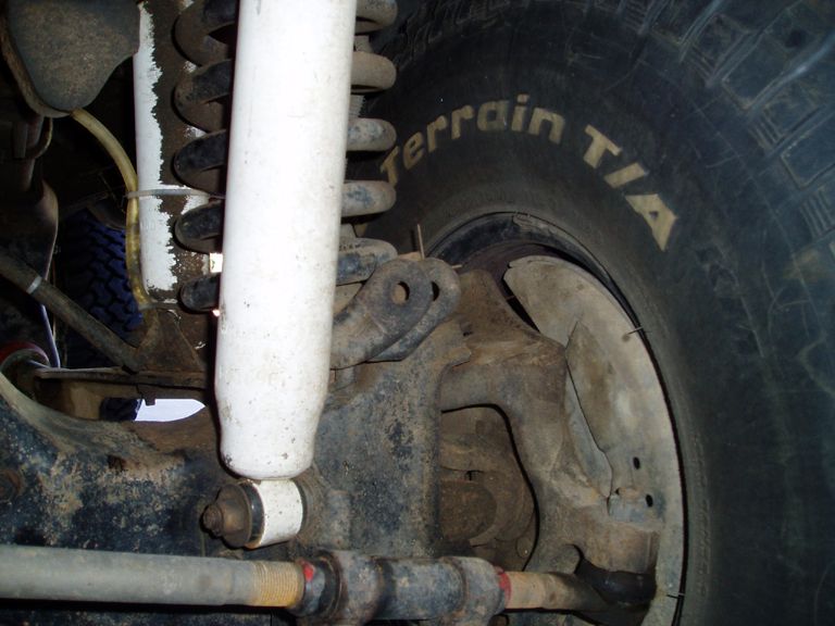 Front suspension close-up with white shock, coil spring and All-Terrain T/A tire