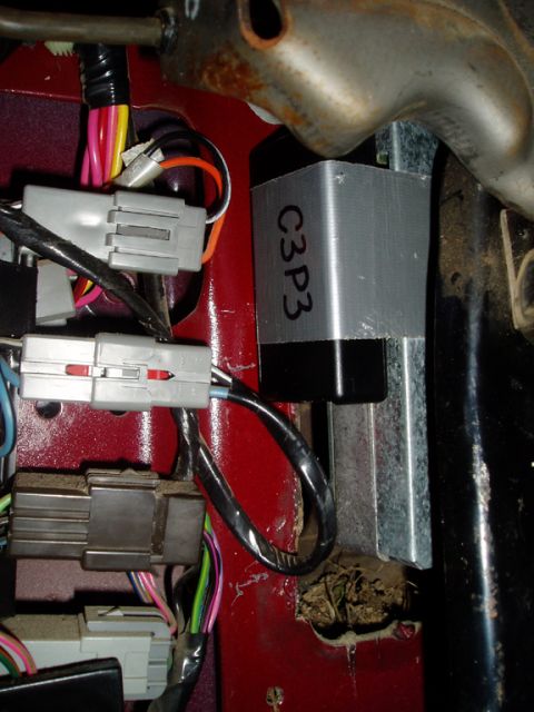 1990 Ford Bronco - Engine-bay firewall detail on a red truck showing a black module wrapped in duct tape and hand-labeled 'C3P3' strapped against a metal brac…