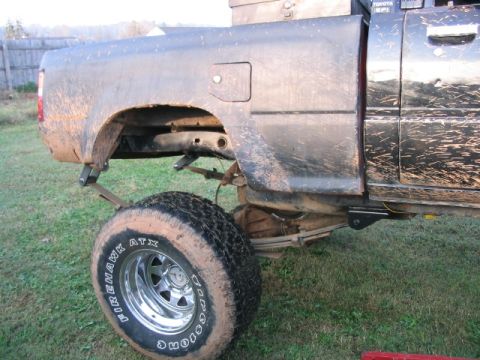 1986 Ford F-150 - Rear view of a muddy black pickup truck, showing the suspension and a large off-road tire. The registry claims it is a 1986 Ford F-150.