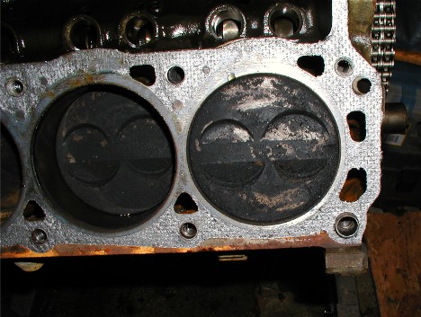 1990 Ford Bronco - Close-up view of an engine block's cylinders and pistons, showing wear and carbon deposits.