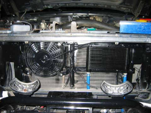 1985 Ford Bronco - Engine bay components including a fan and oil cooler are visible. Text on the lower right reads 'SUPERMOTORS'.