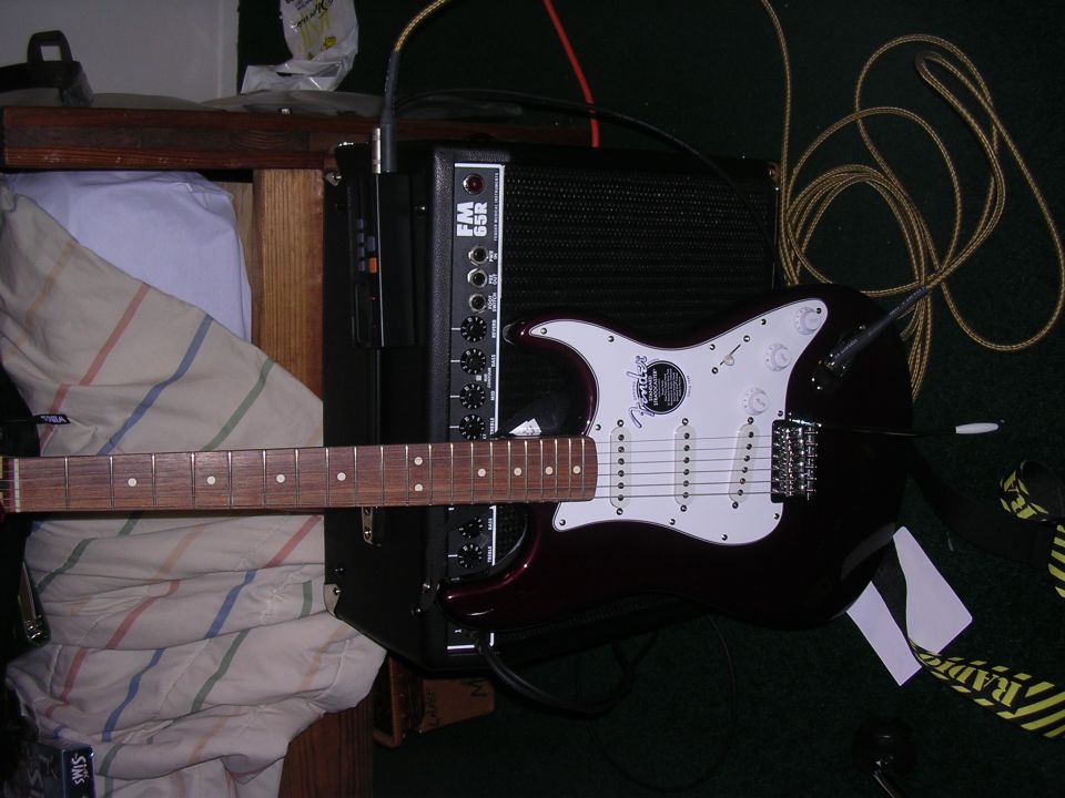 Electric guitar with white pickguard and dark body connected to an amplifier