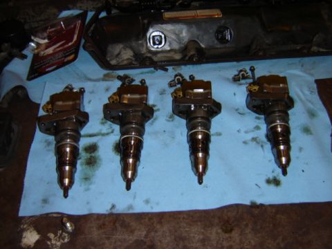 1992 Ford Bronco - Four diesel fuel injectors and a valve cover are laid out on a blue cloth, likely for repair or inspection.