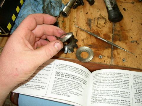 1995 Ford Bronco - A hand holds a gear and washer over an open manual detailing automotive repair procedures.