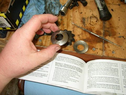 1995 Ford Bronco - A service manual details the removal of a ring gear and bearing assembly, with a hand holding a spacer.
