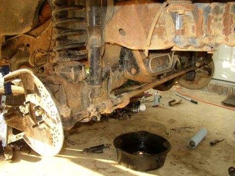 1995 Ford Bronco - Close-up view of the front suspension and brake assembly of a 1995 Ford Bronco, with tools scattered around.