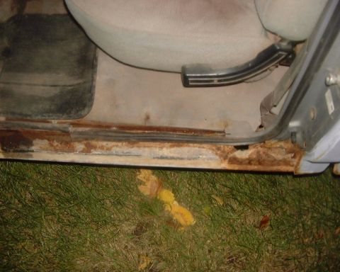 1985 Ford F-150 - The interior door sill of a vehicle shows significant rust damage.