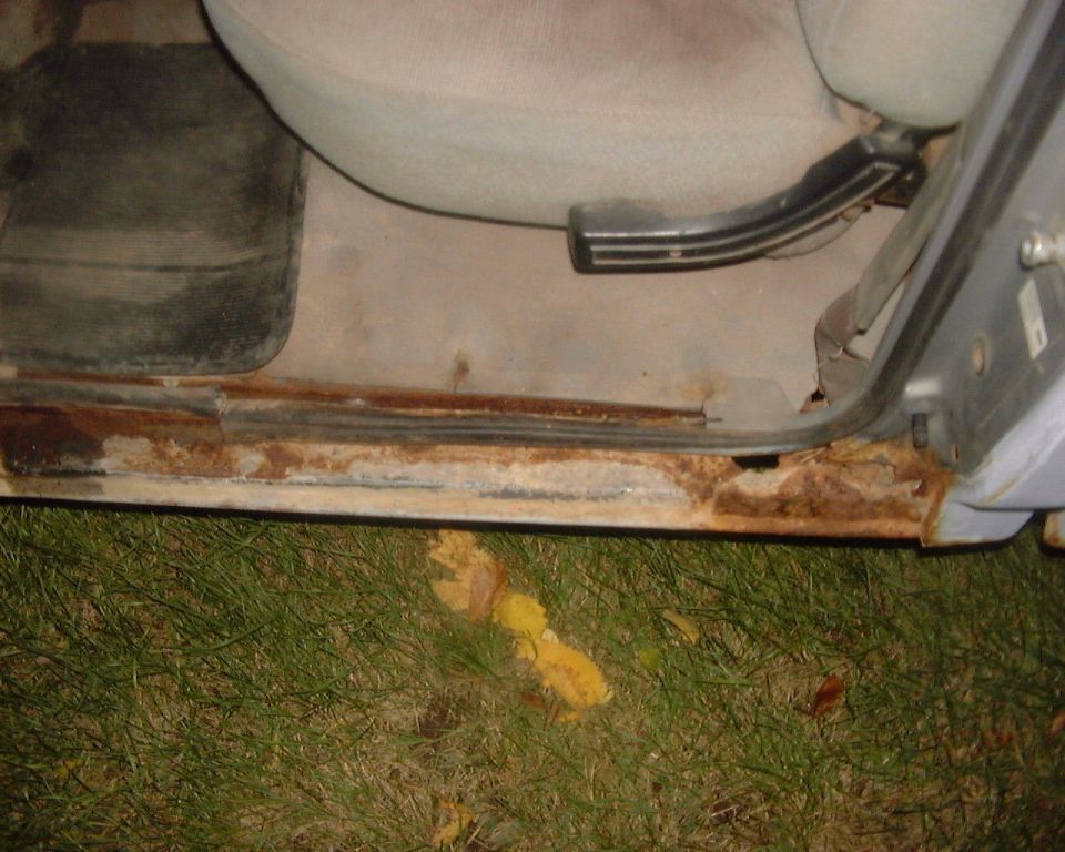 Rusted vehicle door sill and rocker panel with passenger seat visible above