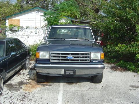 1993 Ford Bronco - This dark blue Ford Bronco, likely from the late 1980s, is parked in an outdoor lot.
