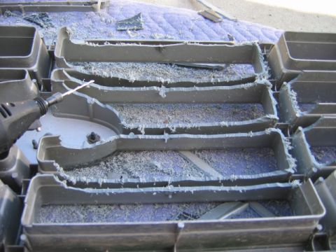 1985 Ford Bronco - A rotary tool is used to cut through a plastic vent, creating dust and debris.