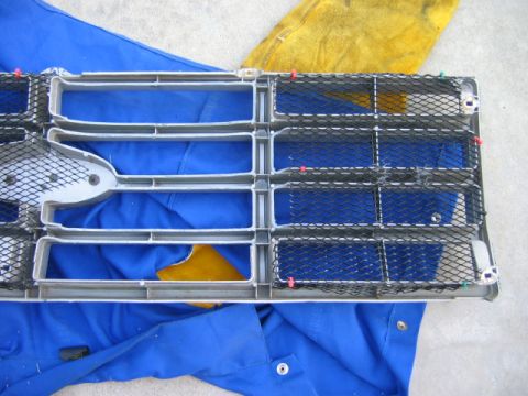 1985 Ford Bronco - A vehicle grille, likely from an older model, is shown disassembled and resting on blue material.