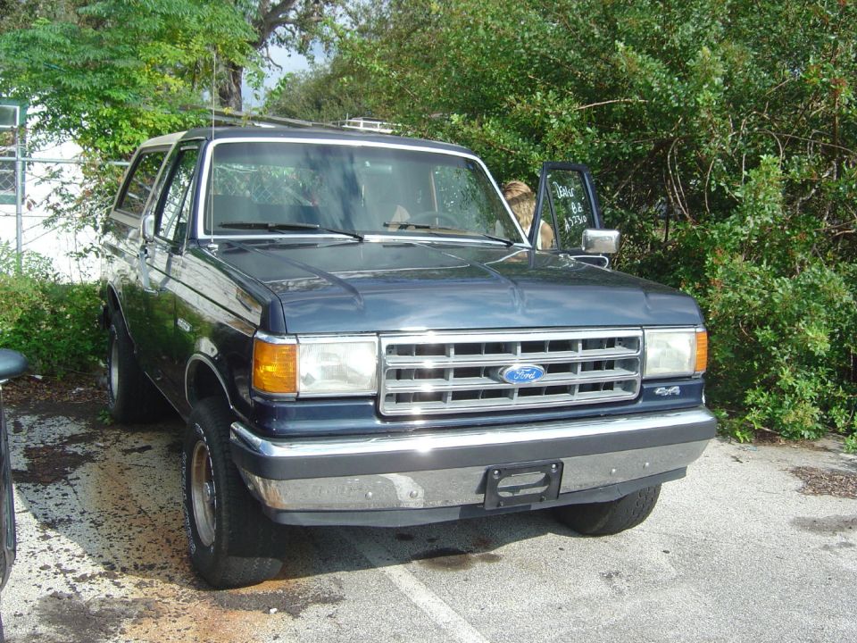 Dark blue Ford Bronco parked outside with the driver's door open