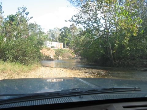1988 Ford Bronco - A vehicle navigates a shallow stream crossing, with trees and a trailer visible on the bank.