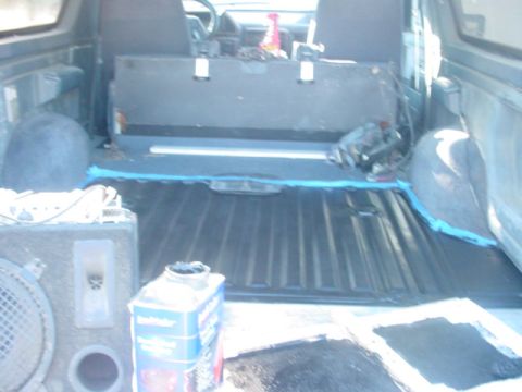 1988 Ford Bronco - The interior of a 1988 Ford Bronco reveals its bedliner, a speaker box, and a bottle of cleaner.