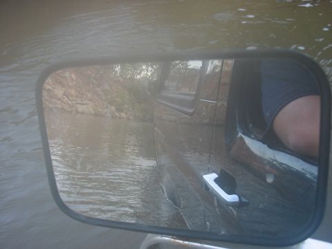 1988 Ford Bronco - A 1988 Ford Bronco navigates through a body of water, as seen from the side mirror.