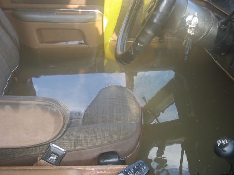 1988 Ford Bronco - Interior of a vehicle submerged in water, with the dashboard and seats visible.