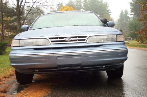 1991 Ford Crown Victoria LTD - The front end of a blue 1991 Ford Crown Victoria LTD is shown on a wet, overcast day.