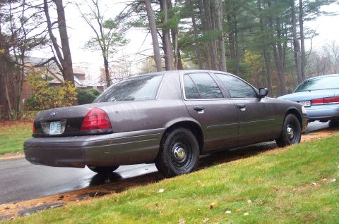 1991 Ford Crown Victoria LTD - Side view of a Ford Crown Victoria, parked on a wet roadside with trees in the background.