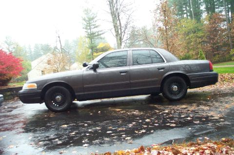 1991 Ford Crown Victoria LTD - A gray Ford Crown Victoria sedan is parked on a wet driveway during autumn.