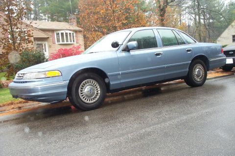 1991 Ford Crown Victoria LTD - A light blue 1992 Ford Crown Victoria sedan is parked on a wet street with a house in the background.