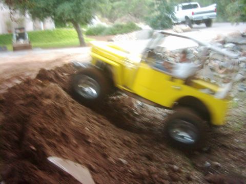 1978 Ford Bronco - A yellow jeep navigates a dirt obstacle while a white pickup truck waits in the background.