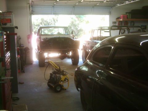 1978 Ford Bronco - A garage scene shows multiple vehicles, including a classic car and two SUVs, one of which appears to be undergoing repairs.