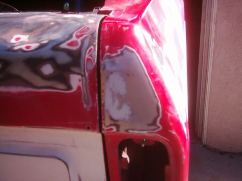 1978 Ford Bronco - Close-up view of a red vehicle's bodywork, showing areas prepared with body filler for repair.