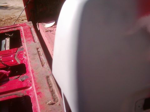 1978 Ford Bronco - The interior of a red truck bed shows some wear and tear, with a white tailgate partially visible.