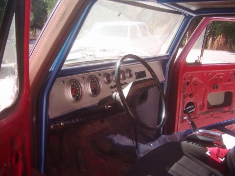 1978 Ford Bronco - Stripped interior of an older truck shot through the open driver's door, showing a custom brushed aluminum dash panel with a large Auto Met…