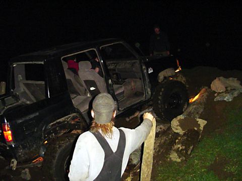 1993 Ford Bronco - An off-road vehicle navigates a challenging course of logs and mud in the dark.