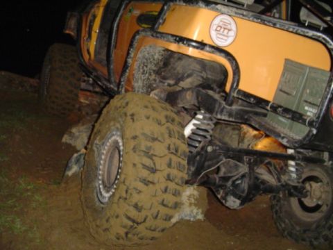 1993 Ford Bronco - Mud-covered off-road vehicle with custom modifications is stuck in dirt.
