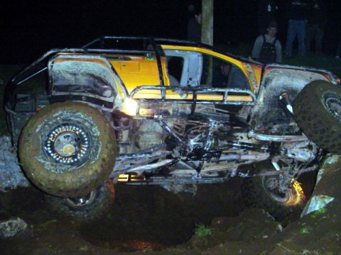 1993 Ford Bronco - Modified SUV with extensive roll cage and large tires navigating difficult terrain.