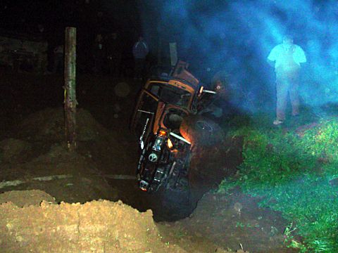 1993 Ford Bronco - An orange SUV has crashed and is overturned in a ditch, with a person standing nearby.