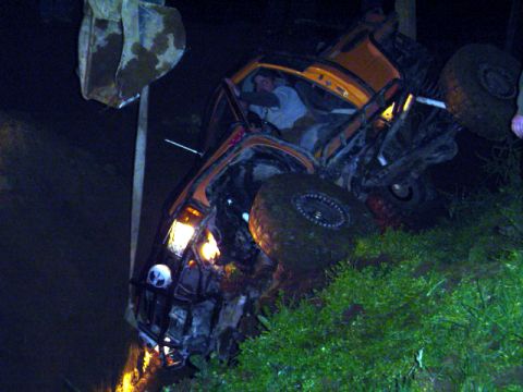 1993 Ford Bronco - An orange off-road vehicle has overturned on its side, with its large tires visible and a person inside the cabin.