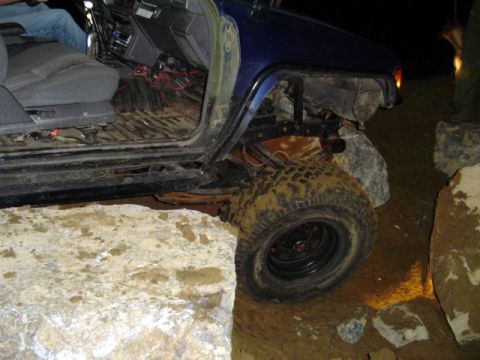 1993 Ford Bronco - This vehicle is positioned precariously between large rocks, with its tires covered in mud.