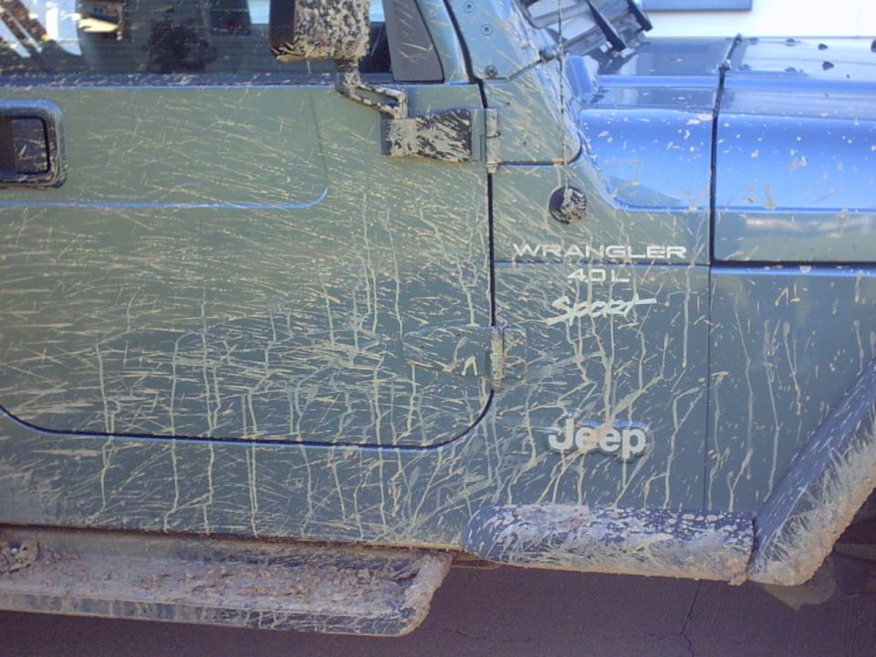 Side view of a muddy Jeep Wrangler with '40L Sport' badging