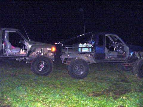 1993 Ford Bronco - Two modified trucks are parked side-by-side on a grassy field at night.