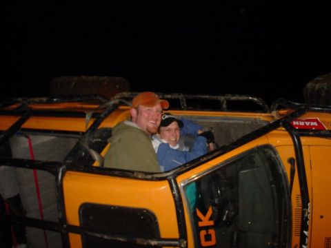 1993 Ford Bronco - Two individuals are seated inside an orange off-road vehicle, appearing to be enjoying an outing.