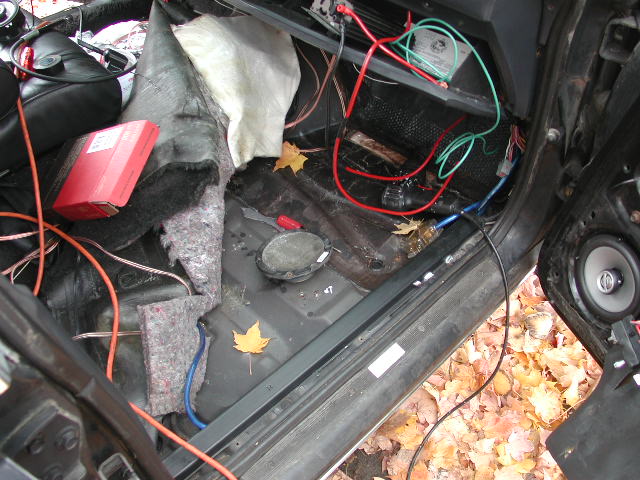 Car interior with exposed wiring, sound deadening, and speakers being installed