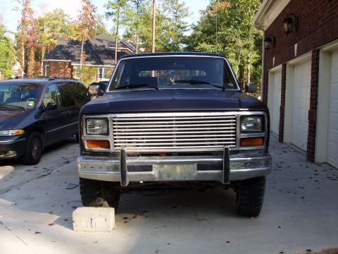 1985 Ford Bronco - Frontal view of a black SUV, possibly from the early 1980s, parked in a driveway.