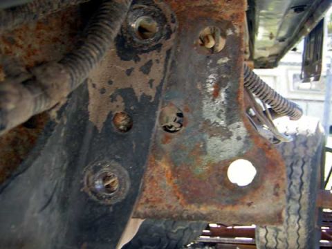 1995 Ford Bronco - This close-up shows a corroded metal bracket with visible wiring and a tire in the background.