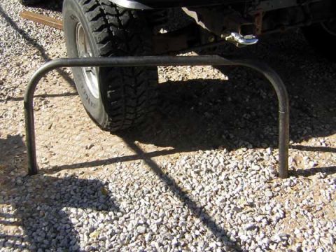 1995 Ford Bronco - A close-up view of a custom rear bumper guard attached to a vehicle, with a focus on the tire and gravel ground.