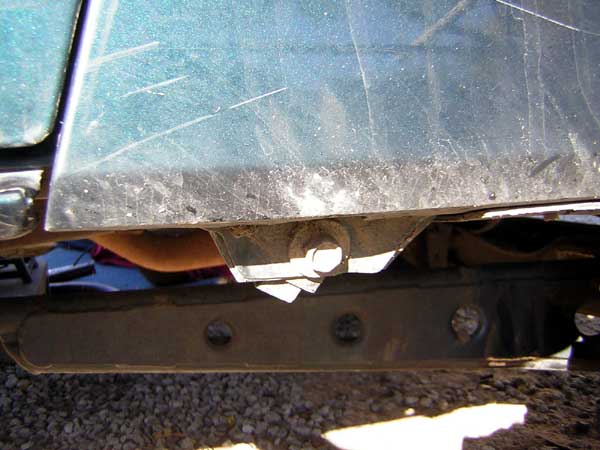 Close-up of a vehicle's frame and body panel, showing rust and dirt