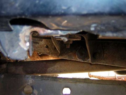 1995 Ford Bronco - Close-up view of the undercarriage of a vehicle, showing rusty frame components and suspension.