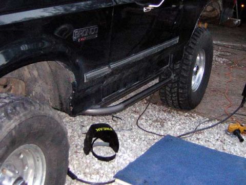 1995 Ford Bronco - The side of a black Ford Bronco is shown, its XLT trim and custom side steps.