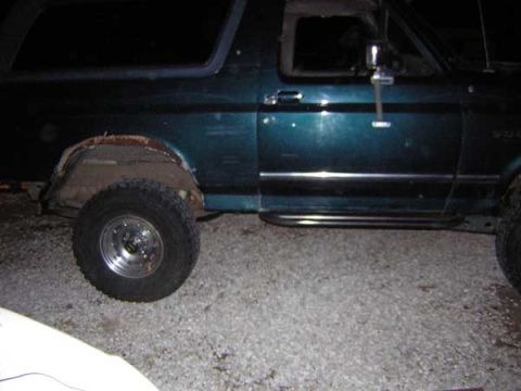 1995 Ford Bronco - Side view of a teal SUV with visible fender damage and aftermarket side steps.